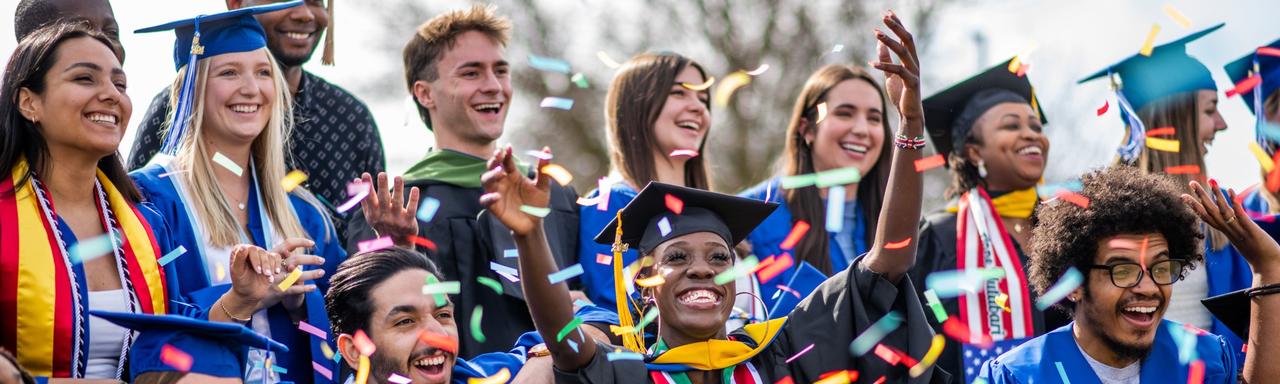 Grads celebrate with confetti in front of the GVSU letters